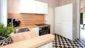 A modern kitchen with a wooden countertop, stainless steel appliances, and a checkered floor. - Fresh Breeze Vacation Home 23 (Lübeck-Travemünde)