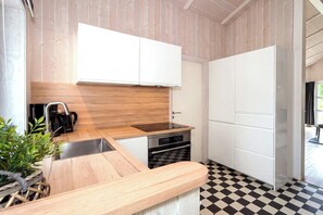 A modern kitchen with a wooden countertop, stainless steel appliances, and a checkered floor. - Fresh Breeze Vacation Home 23 (Lübeck-Travemünde)