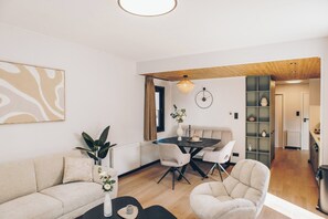 Uma sala de estar moderna com sofá, mesa de centro e área de jantar com cadeiras.