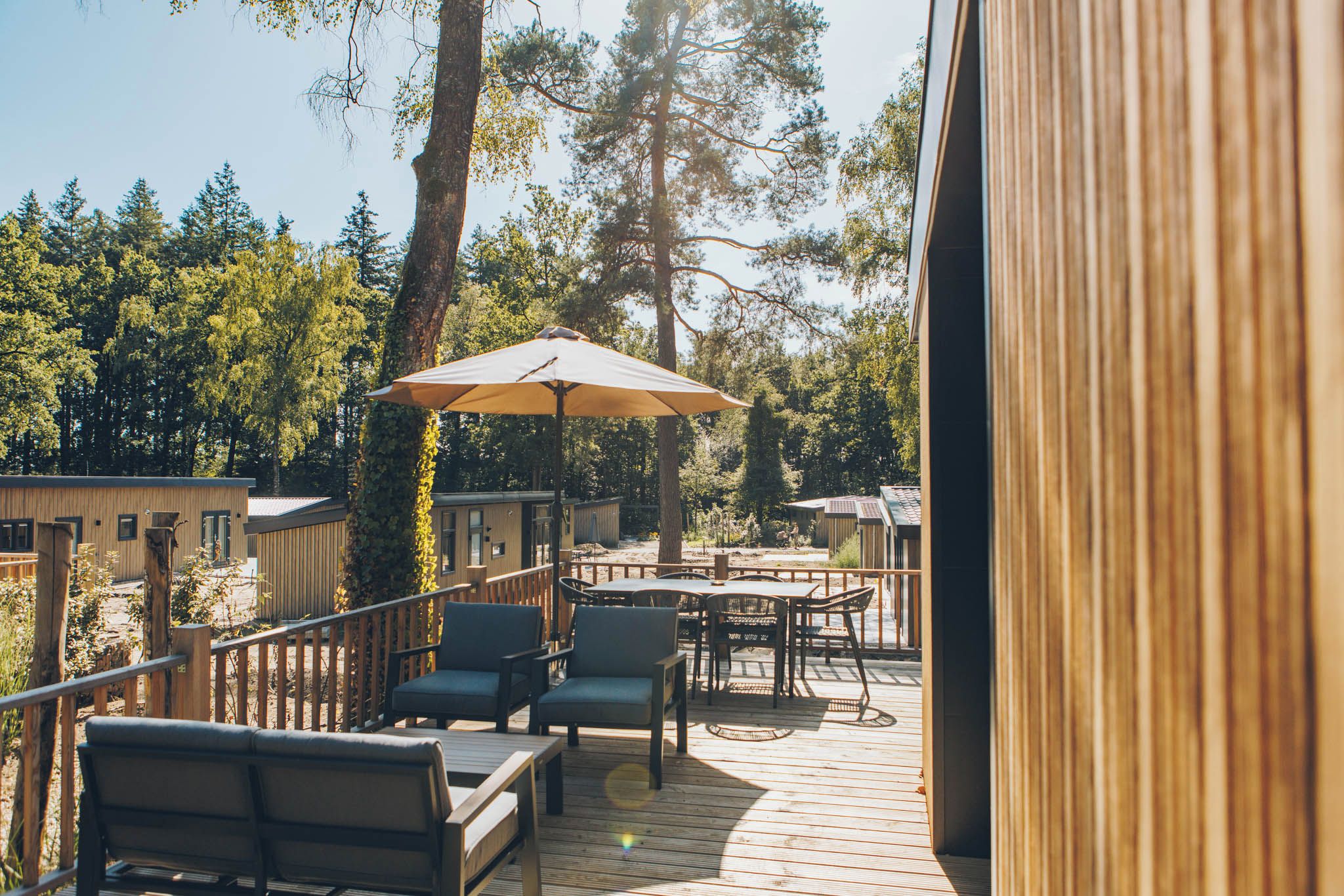 Una terraza de madera con mobiliario exterior y un gran paraguas.