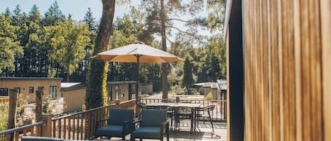 Una terraza de madera con mobiliario exterior y un gran paraguas.