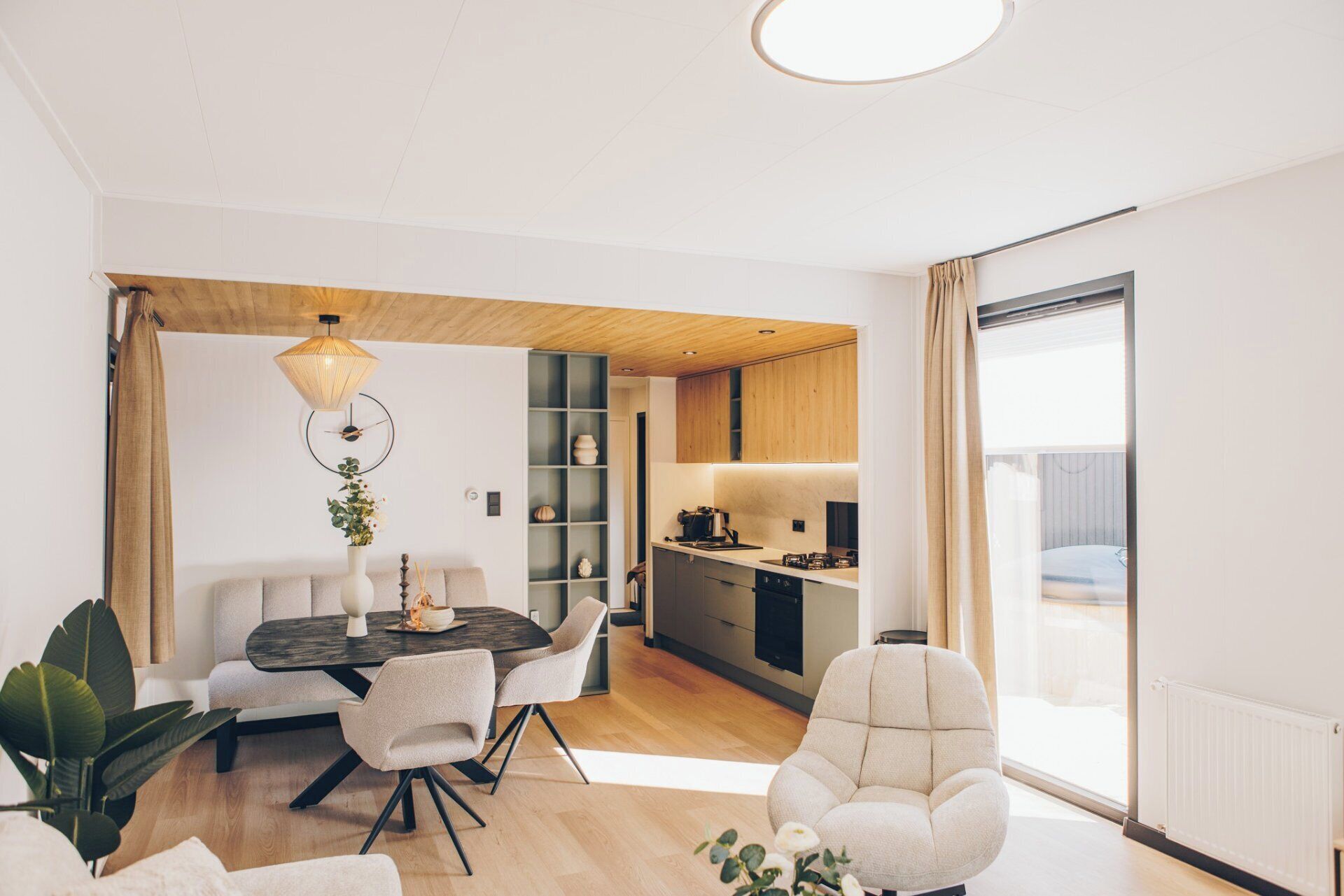 A modern living space with a dining area, kitchen, and seating area.