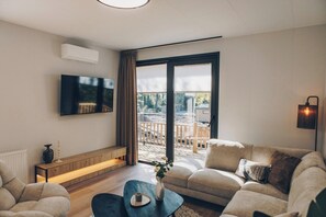 A modern living room with a sofa, a coffee table, a TV mounted on the wall, and a sliding glass door leading to an outdoor area.