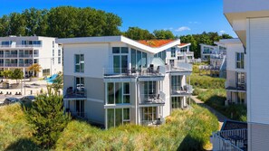 Ein modernes Mehrfamilienhaus mit Balkonen, großen Fenstern und einer Flachdach.