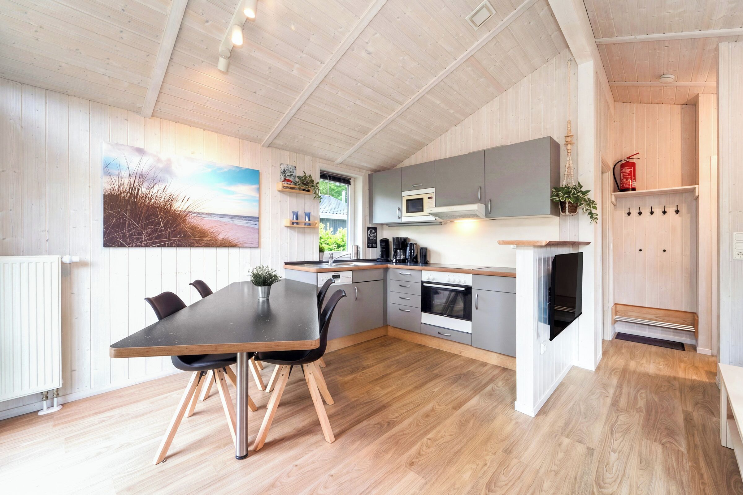 Una cocina moderna con comedor, piso de madera y vistas al exterior.