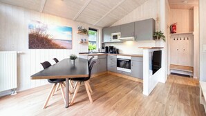 Uma cozinha moderna com área de refeições, piso de madeira e vista para o exterior.