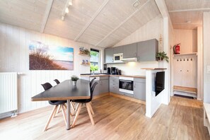 Eine moderne Küche mit Essbereich, Holzboden und Blick ins Freie.