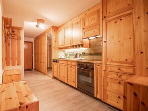 Eine Holz-Küche mit eingebautem Backofen und einer gefliesten Spritzschutzwand.