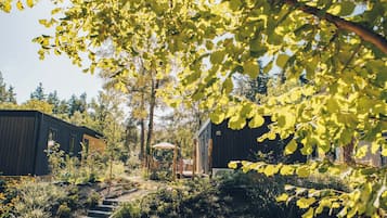 A garden with a wooden deck, a small pavilion, and two buildings with a rustic design.