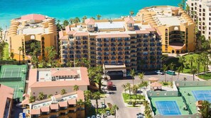 Een hotel met meerdere verdiepingen, een tennisbaan en een zwembad.