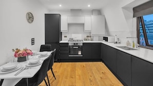 Een moderne keuken met een eethoek, voorzien van een fornuis, magnetron en spoelbak.