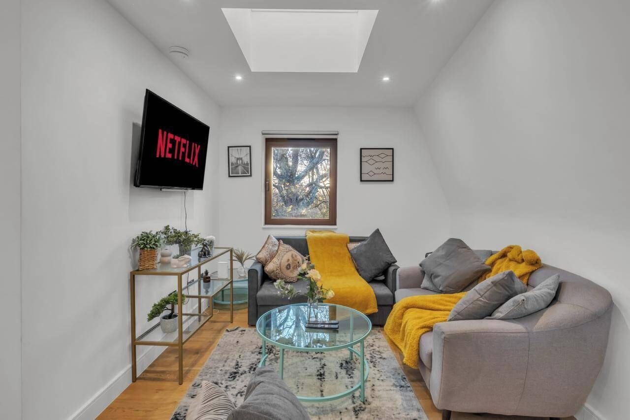Een moderne woonkamer met een flatscreen televisie, een bank, een salontafel en een raam met uitzicht.