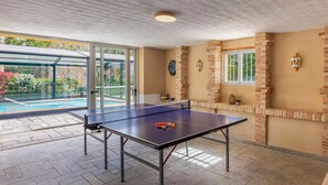 Ein Tischtennis-Tisch mit Netz, eine Dartscheibe und eine Uhr an der Wand.