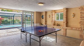 Ein Tischtennis-Tisch mit Netz, eine Dartscheibe und eine Uhr an der Wand.