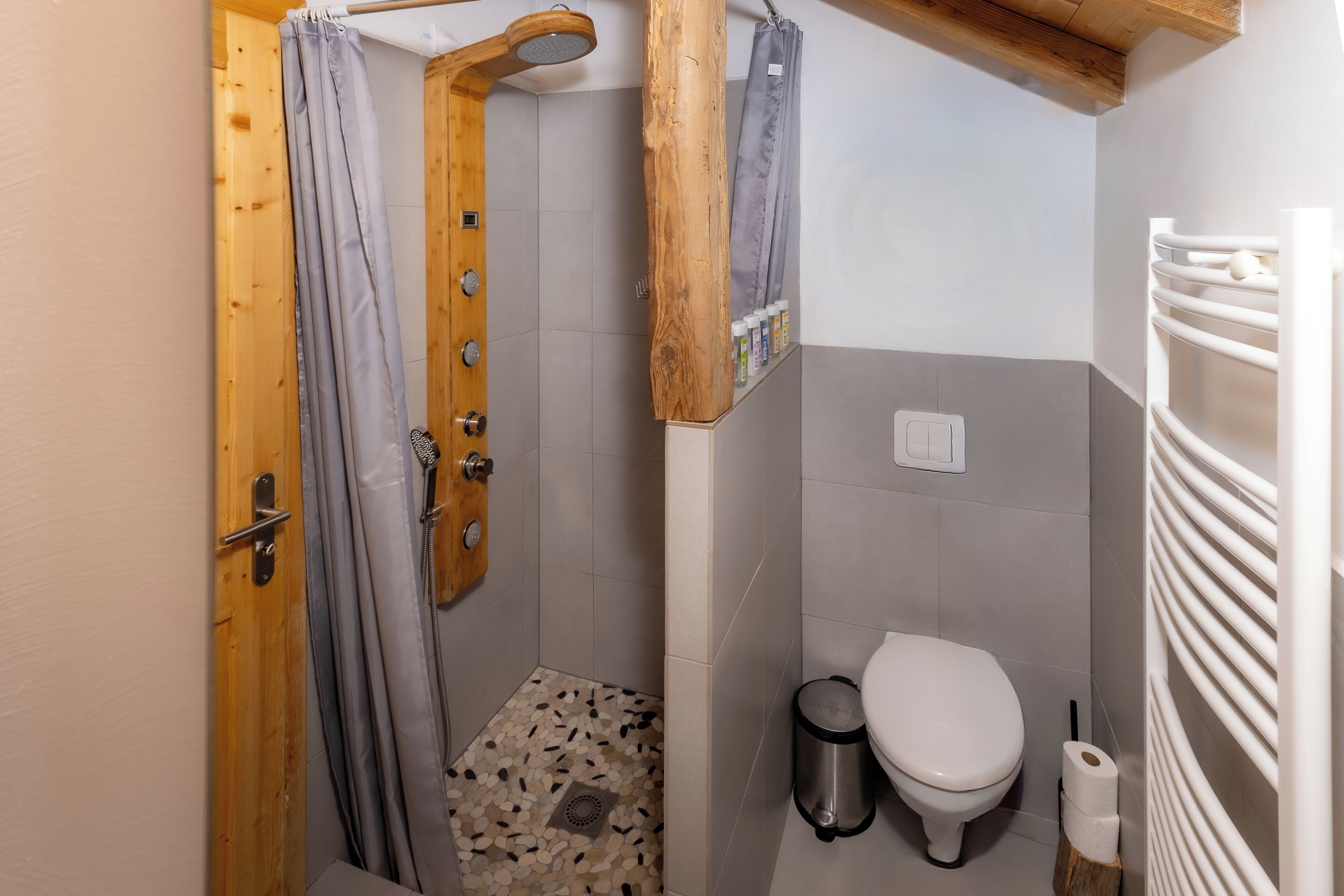 Een kleine badkamer met douche, toilet en een handdoekhouder.