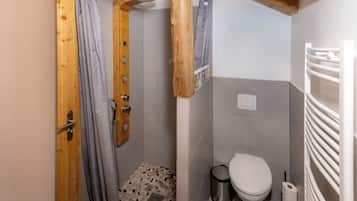Een kleine badkamer met douche, toilet en een handdoekhouder.