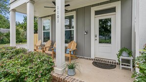 A porch with two wooden chairs, a small table, and a potted plant. - The Reverie - Downtown Pensacola - Convenient Corner Lot - Great For Business Travelers - Fast WiFi (Pensacola)