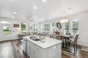 A modern kitchen with a central island, dining area with a table and chairs, and a ceiling fan. - The Reverie - Downtown Pensacola - Convenient Corner Lot - Great For Business Travelers - Fast WiFi (Pensacola)