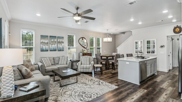 A spacious living room with a sofa, coffee table, and a rug. There is a dining area with chairs and a table. A kitchen with a sink and cabinets is visible. - The Reverie - Downtown Pensacola - Convenient Corner Lot - Great For Business Travelers - Fast WiFi (Pensacola)