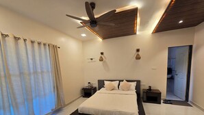 Um quarto moderno com uma cama grande, um ventilador de teto e um banheiro visível por uma porta aberta.