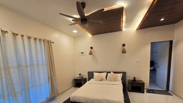 A modern bedroom with a large bed, a ceiling fan, and a bathroom visible through an open door.
