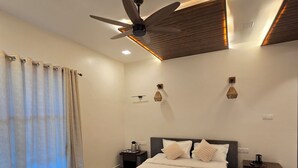 Quarto moderno com uma cama grande, um ventilador de teto, mesas de cabeceira e um tapete escuro.