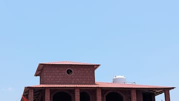 Um edifício de dois andares com telhado de telhas vermelhas, várias arcadas e uma varanda com grades decorativas.