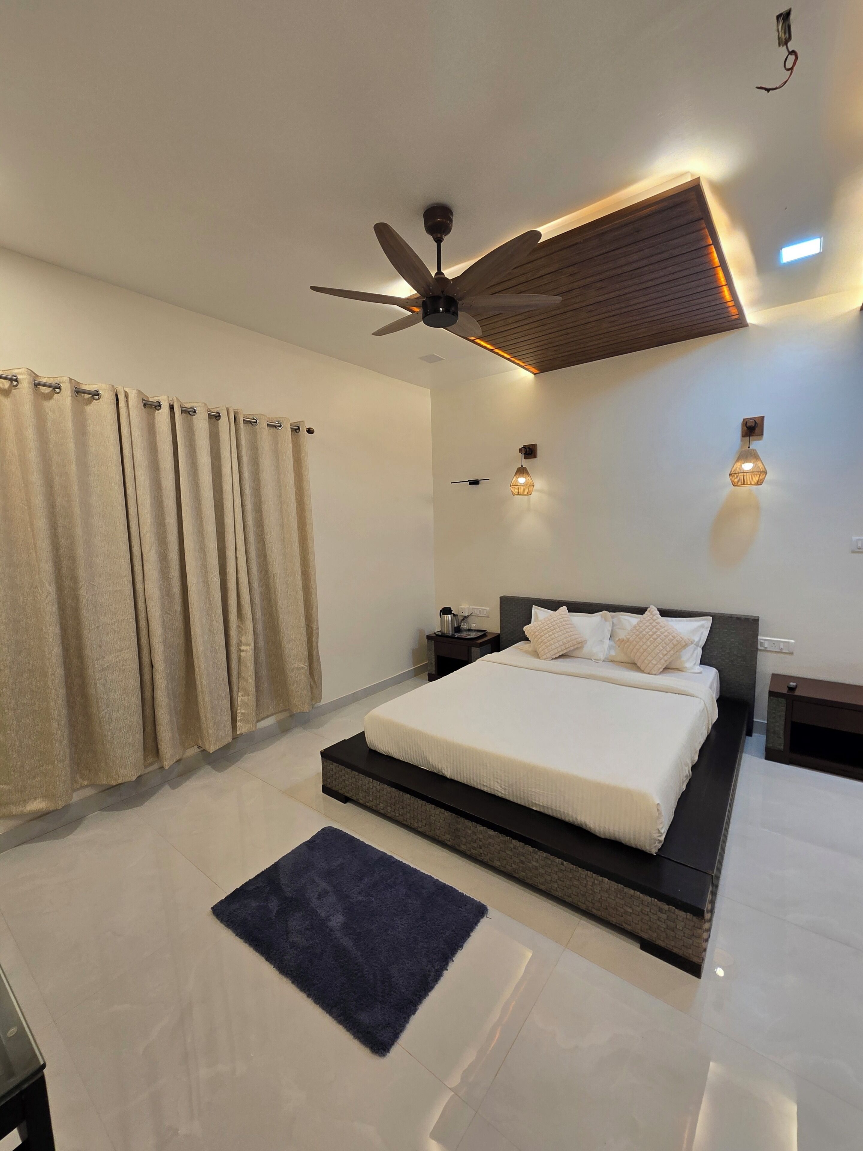 A modern bedroom with a large bed, a ceiling fan, and two wall-mounted lights.
