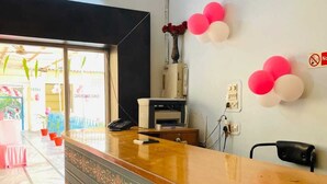 Un mostrador de recepción con un teléfono, un florero con flores y un cartel de 'No Fumar' en la pared.