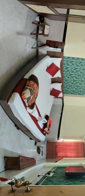 A room with a bed, a small table, and a green textured wall. - Hotel Akshey (Jodhpur)
