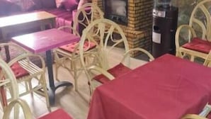 A restaurant interior with stone walls, a brick fireplace, and red tablecloths.