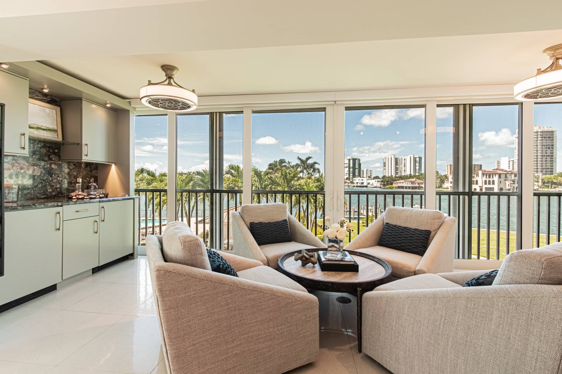 A spacious balcony with a view of the city skyline, a modern kitchen with a marble countertop, and comfortable seating with a round coffee table.