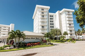 A multi-story hotel with a prominent entrance, palm trees, and a clear sky. - Park Shore-Luxury 3BR/3BA condo on Venetian Bay-boat slip, carport, private Park Shore beach pass (Naples)