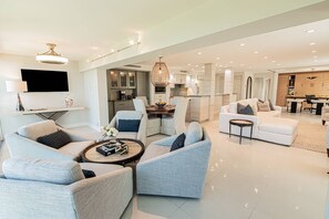 A spacious living area with a modern kitchen, a dining table, and a seating arrangement. - Park Shore-Luxury 3BR/3BA condo on Venetian Bay-boat slip, carport, private Park Shore beach pass (Naples)