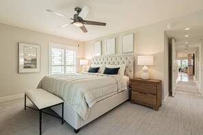 A bedroom with a bed, a bench, a nightstand, a ceiling fan, and framed artwork on the wall. - Park Shore-Luxury 3BR/3BA condo on Venetian Bay-boat slip, carport, private Park Shore beach pass (Naples)