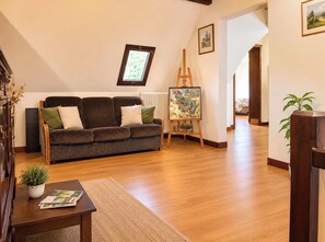 A living room with a sofa, a painting on easel, and a potted plant. - Spacious vacation rental in the heart of the Périgord Noir (Le Bugue)