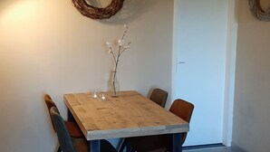 Un'area pranzo con un tavolo di legno, sedie e un vaso con fiori.