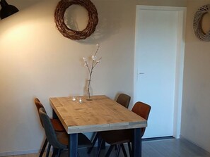 A dining area with a wooden table, chairs, and a vase with flowers. - Vakantieboerderij Tergracht - t Huuske by Interhome (Epen)
