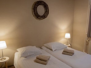 A hotel room with two beds, each with a pillow and a folded towel. There is a wall-mounted mirror above the beds and a lamp on each side of the room. - Vakantieboerderij Tergracht - t Huuske by Interhome (Epen)