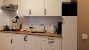 Una cucina con mobili bianchi, una cappa in acciaio inossidabile, un lavello e una macchina per il caffè.
