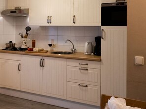 A kitchen with white cabinets, a stainless steel range hood, a sink, and a coffee maker. - Vakantieboerderij Tergracht - t Huuske by Interhome (Epen)