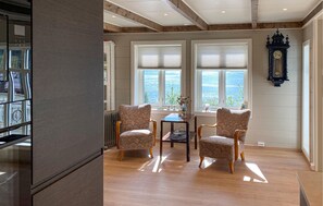 A room with a wooden floor, two upholstered chairs, a small table, and a window with a view. - Gorgeous home in Fiskåbygd with house a panoramic view (Fiskåbygd)