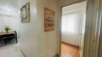 A hallway with a dining area on the left, a motivational quote on the wall, and a door leading to another room.