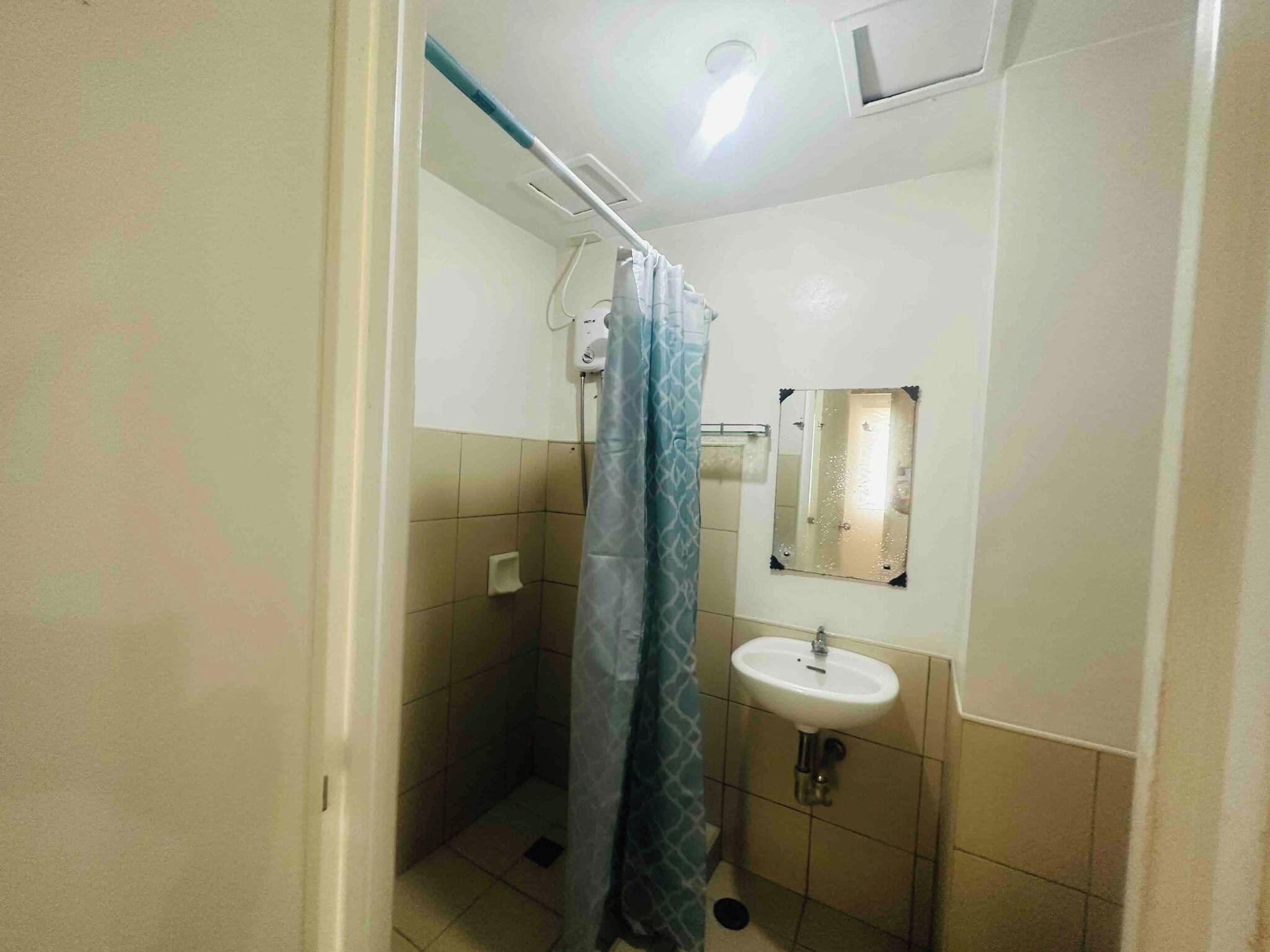 Un baño pequeño con cortina de ducha, lavamanos y espejo.