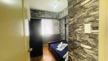 Habitación de hotel con cama, suelo de madera, pared de piedra y una puerta.