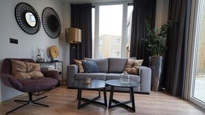 Moderni olohuone, jossa on sohva, nojatuoli ja sohvapöytä.