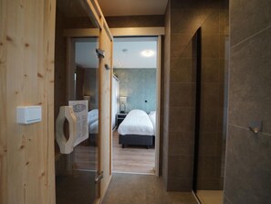 Ein Hotelzimmer mit Holztür, einem Bett, einem Nachttisch und einem Beistelltisch.