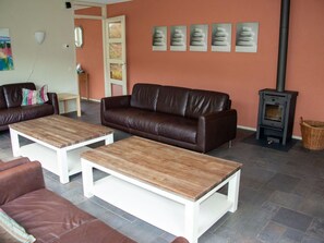 Ein Wohnzimmer mit einem braunen Ledersofa, zwei Holztischen und einem Kamin aus Stein.