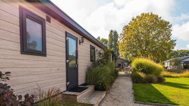 A modern house with a wooden exterior, a black door, and a gravel pathway leading to a grassy yard. - Vakantiepark Aan de Maas - Maas Lande | 4p by Interhome (Kerkdriel)