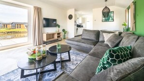 A modern living room with a large sofa, a coffee table, and a flat-screen TV. - Vakantiepark Aan de Maas - Maas Lande | 4p by Interhome (Kerkdriel)